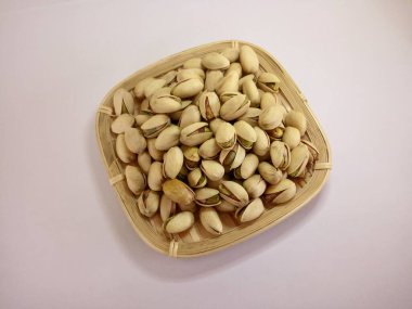 Bambu sepetindeki şam fıstıkları beyaz arka planda izole edilmiş.
