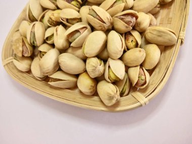 Bambu sepetindeki şam fıstıkları beyaz arka planda izole edilmiş.