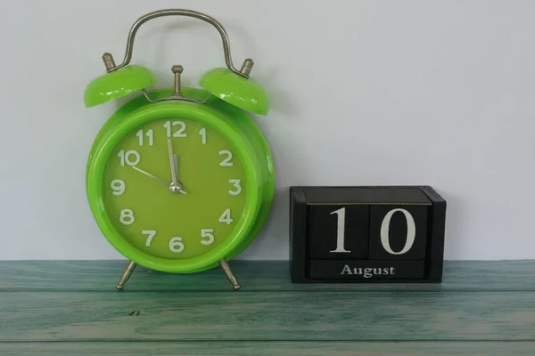 green alarm clock and cube calendar date with August month concept