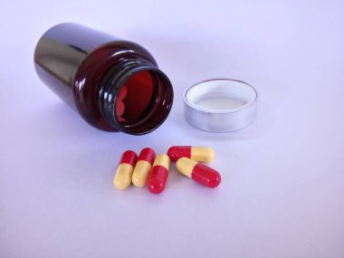 Beyaz arka planda şişesi olan haplar veya kapsüller