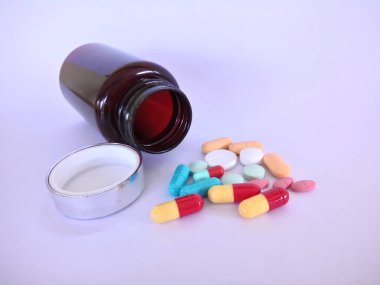 Beyaz arka planda şişesi olan haplar veya kapsüller