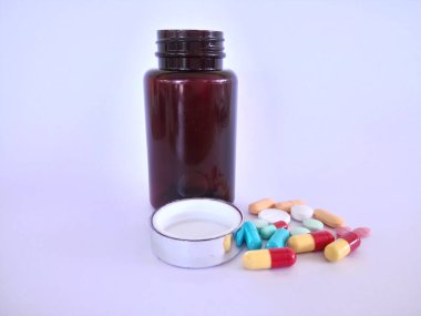 Beyaz arka planda şişesi olan haplar veya kapsüller