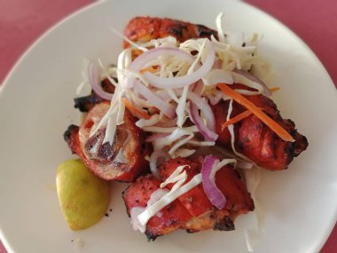 Tandır tavuğu. Yoğurt ve baharatla terbiye edilmiş kızarmış tavuk tarafından hazırlandı. Renkli ya da ahşap arka planda salata ile servis edilen bacak parçası. Seçici odak