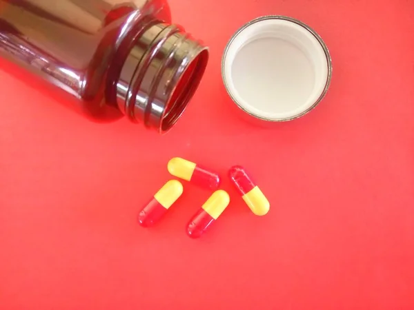 在红色背景下隔离的瓶子和药丸 — 图库照片