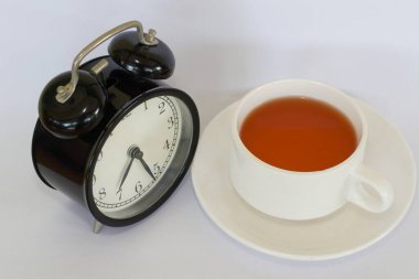 a cup of tea with alarm clock on white background