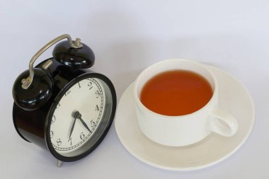 a cup of tea with alarm clock on white background