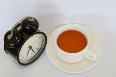a cup of tea with alarm clock on white background