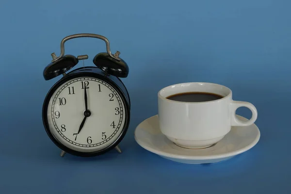 Çalar Saat Mavi Arka Planda Bir Fincan Kahve — Stok fotoğraf