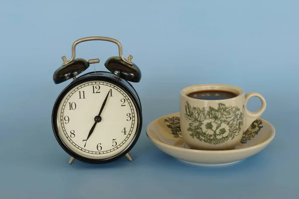 Wekker Een Kop Koffie Tegen Blauwe Achtergrond — Stockfoto