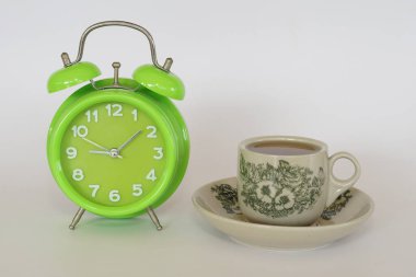 Beyaz arka planda izole edilmiş bir fincan çayla birlikte çalar saat.