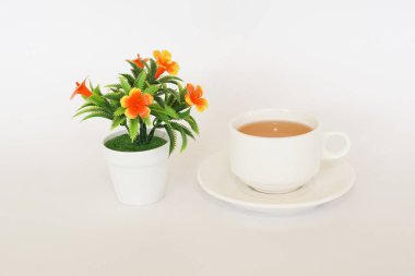 Çiçek ve bir fincan çay beyaz arka planda.