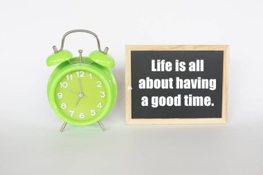 Motivasyon alıntıları olan yeşil alarmlı saat. Hayat güzel vakit geçirmekten ibarettir..
