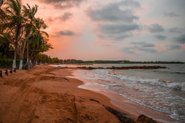 Tropikal bir sahil manzarasının güzel bir görüntüsü. Güneş harika ve renkli bir gündoğumunda doğuyor.