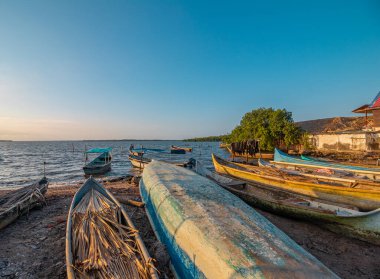Bir grup renkli kır teknesi balık tutma faaliyetlerinden hemen sonra bir plajda dinleniyor.
