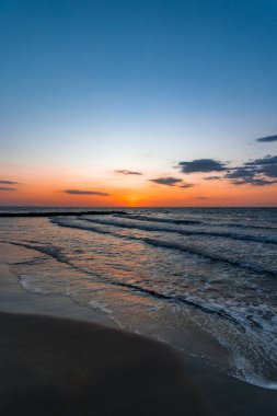 Tropikal bir sahil manzarasının güzel bir görüntüsü. Güneş harika ve renkli bir günbatımında batıyor.