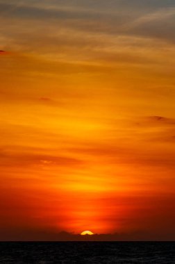 Tropikal bir sahil manzarasının güzel bir görüntüsü. Güneş harika ve renkli bir günbatımında batıyor.