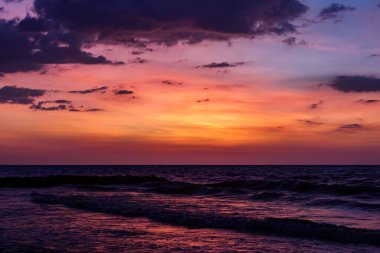 Tropikal bir sahil manzarasının güzel bir görüntüsü. Güneş harika ve renkli bir günbatımında batıyor.