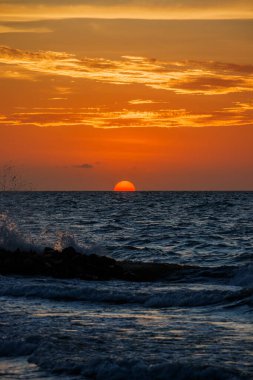 Tropikal bir sahil manzarasının güzel bir görüntüsü. Güneş harika ve renkli bir günbatımında batıyor.