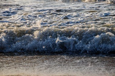 Hareket eden okyanus dalgalarının güzel manzarası yavaşça kumlu kıyıya ulaşıyor.