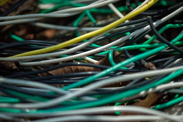 Closeup of several electrical wires forming curved lines with a lot of chaos like if they were abandoned