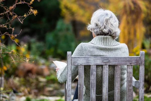 Ältere Frau Liest Buch Herbstlichen Garten — Stockfoto