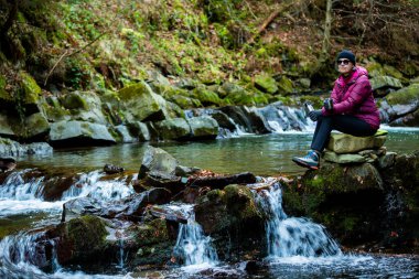 Olgun bir kadın, nehirde, dağlarda sıcak kahve içer..