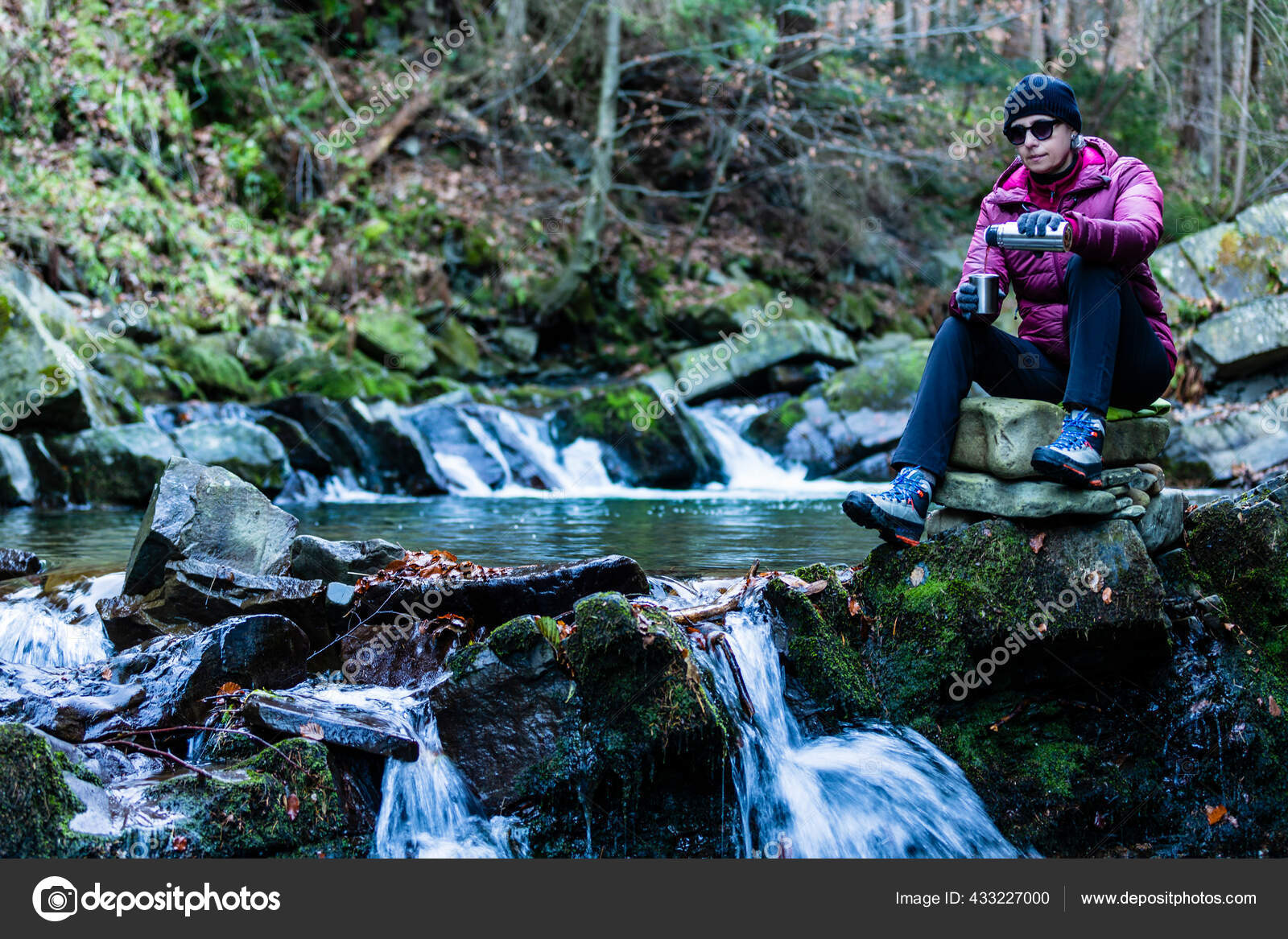 Thermos with a hot drink on mountain waterfall Stock Photo by