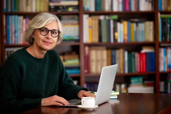 İnterneti dizüstü bilgisayarda kullanan yaşlı bir kadın. Yaşlıların modern yaşam tarzı..
