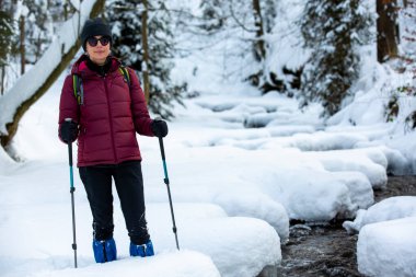Kış manzarasında İskandinav Yürüyüşü pratiği yapan bir kadın. Yaşlıların aktif yaşam tarzı. 