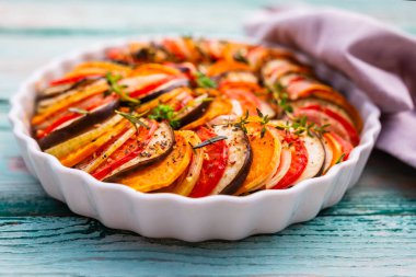 Ahşap bir arka planda beyaz bir fırında lezzetli sebzeli ratatouille..