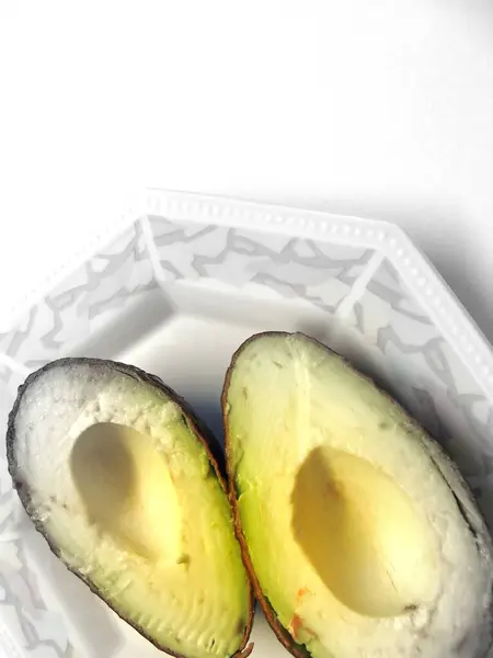 Avocado Helften Een Porseleinen Bord — Stockfoto
