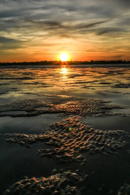Canlı bir günbatımı Broome 'daki Roebuck Körfezi' ni aydınlatır. Gelgit çamurları boyunca parlak turuncu ve pembe renkleri yansıtır. Bu sakin kıyı manzarası Batı Avustralyalı Kimberley bölgesinin doğal güzelliğini ve dingin atmosferini yakalar..