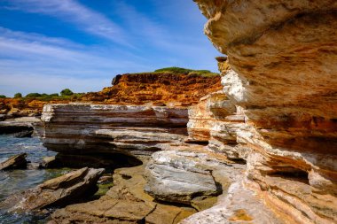 Gantheaume Point 'in engebeli kaya oluşumları berrak bir gökyüzünün altında turkuaz sularla buluşuyor. Bu manzaralı Batı Avustralya kıyı şeridi dramatik uçurumlar, eşsiz jeolojik özellikler ve Broome bölgesinin doğal güzelliğini sergiliyor..