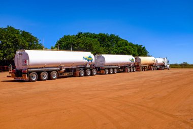 Engebeli Avustralya kırsalının ortasına park edilmiş büyük bir yol treni, uzak ulaşımı ve uçsuz bucaksız, çorak manzarayı vurguluyor. Görüntü taşra lojistiğinin, sert çevrenin ve ikonik Avustralya taşımacılık kültürünün ölçeğini vurguluyor..