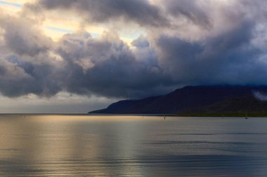 Cairns Harbour 'un panoramik manzarasında, kıyı boyunca uzanan liman ve yemyeşil yemyeşil kayıklarla tropikal kıyı şeridine ulaşan köpüklü sular görülüyor. Sahne, Queensland şehrinin canlı sahil cazibesini yakalıyor..