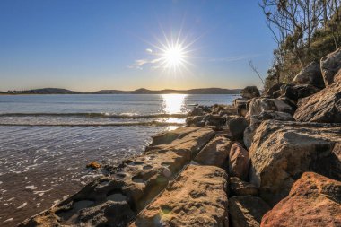 Güçlü okyanus dalgaları Boat Harbour 'daki engebeli kayalık kıyı şeridine çarparak beyaz deniz spreyi ve dramatik hareketler yaratıyor. Sahne, Avustralya kıyı manzarasının ham enerjisini ve doğal güzelliğini parlak bir gökyüzü altında yakalıyor..