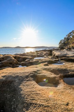 Güçlü okyanus dalgaları Boat Harbour 'daki engebeli kayalık kıyı şeridine çarparak beyaz deniz spreyi ve dramatik hareketler yaratıyor. Sahne, Avustralya kıyı manzarasının ham enerjisini ve doğal güzelliğini parlak bir gökyüzü altında yakalıyor..