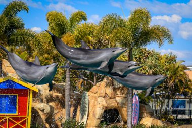 Bir yunus sürüsü uyum içinde zarif bir şekilde sudan atlıyor, dinamik ve neşeli bir sahne yaratıyor. Görüntü deniz yaşamını, neşeli davranışları ve hareket halindeki vahşi yaşamın güzelliğini vurguluyor..