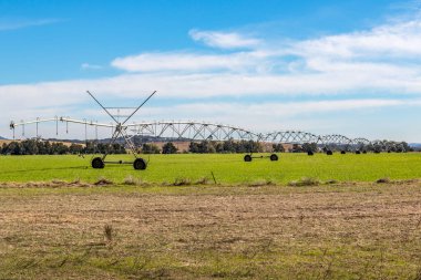 Seyahat eden bir sulama suları geniş tarım arazileri, parlak bir gökyüzünün altındaki ekinlere yaşam veren nem. Görüntü, modern tarım uygulamalarını, kırsal tarım ölçeğini ve Avustralya 'daki su yönetiminin verimliliğini vurguluyor..