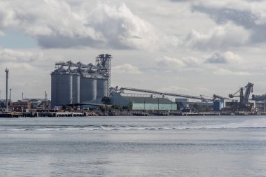 Avustralya 'nın en büyük nakliye limanlarından Newcastle Limanı' nın hareketli manzarası. Bölgesel Yeni Güney Galler 'deki deniz ticaretinin ölçeğini ve önemini vurgulayan kargo gemileri, vinçler ve endüstriyel altyapı sahne üzerinde egemenlik kuruyor..