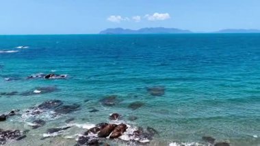 Stunning aerial footage showcasing the vibrant turquoise waters and rugged rocky coastline of Hydeaway Bay. Clear shallows, textured reef edges, and dramatic shoreline curves create a striking and cinematic coastal scene full of colour