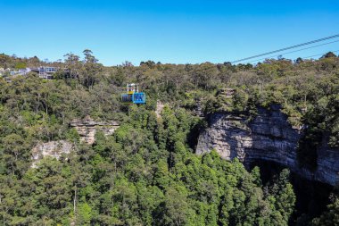 Mavi Dağlar 'daki Sahne Dünyası' nda Jamison Vadisi 'nde orman manzarası ve kumtaşı kayalıkları ile seyahat eden kablo araba..