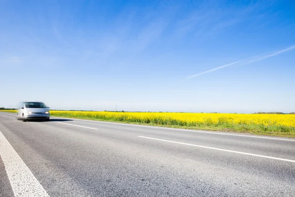 Auto na silnici krajinou krásné žluté pole — Stock fotografie