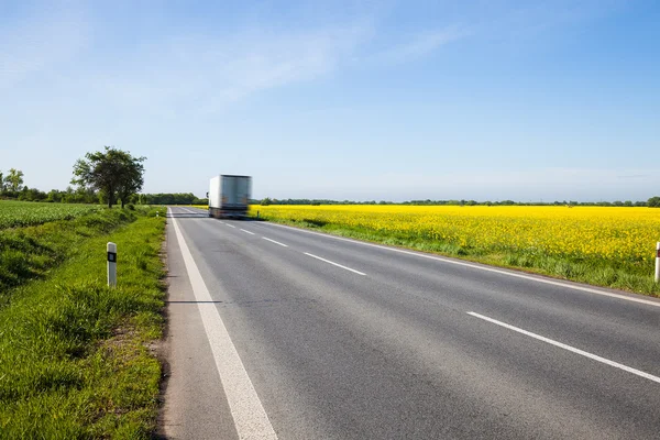 Camion in movimento la bella strada di campagna campo giallo — Foto Stock