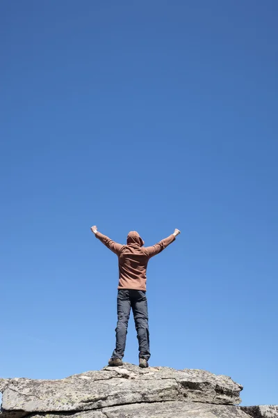 Homem em pé no topo da montanha sobre o céu azul — Fotografia de Stock