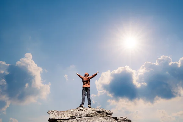 Mann steht auf dem Gipfel des Berges über blauem und sonnigem Himmel — Stockfoto