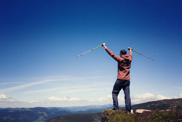 Homem com postes de trekking em pé no topo da montanha — Fotografia de Stock