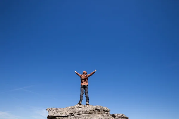 Hombre de pie en la cima de la montaña sobre el cielo azul —  Fotos de Stock