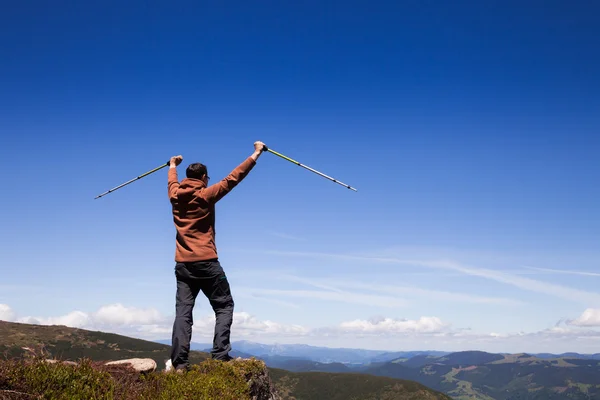 Mann mit Wanderstöcken steht auf dem Gipfel des Berges — Stockfoto