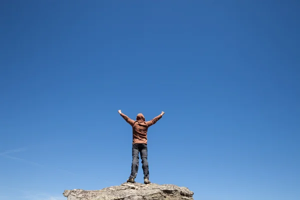 Mand stående på toppen af bjerget over blå himmel - Stock-foto